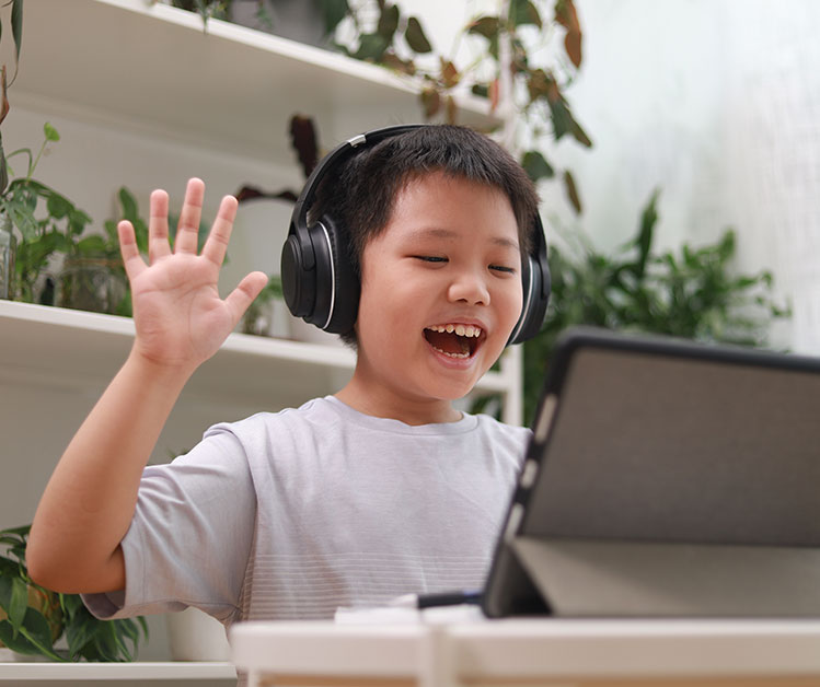 Cheerful child using a tablet for online learning at New Start Education online class